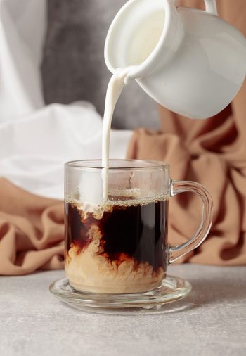 Pouring milk into a cup of coffee