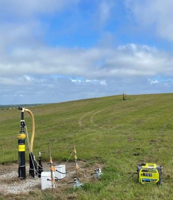 A landfill gas sampling system connected to a pipe coming out of a grassy hill
